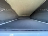 RV rental pop-top: Interior view of the bed area with grey fabric walls and a light, textured roof above.
