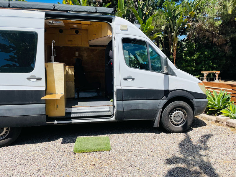 White camper van with custom wood interior, sink, and open door on gravel. Ideal for an RV rental adventure. — photo 7