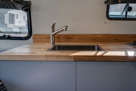 Bright RV rental kitchen with modern stainless steel sink, faucet, and warm wood countertops.