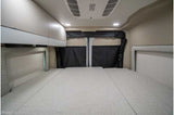 View inside an rv rental camper van: light-colored interior with a large bed, overhead cabinets, and rear privacy covers.