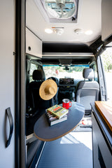 Cozy rv rental interior featuring a flexible table with books and mug, plus a ceiling fan for comfort.