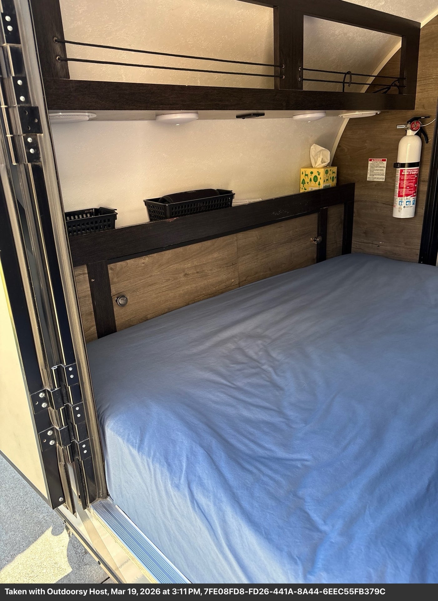  is parked and ready for an Outdoorsy adventure.|Inside this RV rental: a cozy bedroom with a blue bed — photo 2