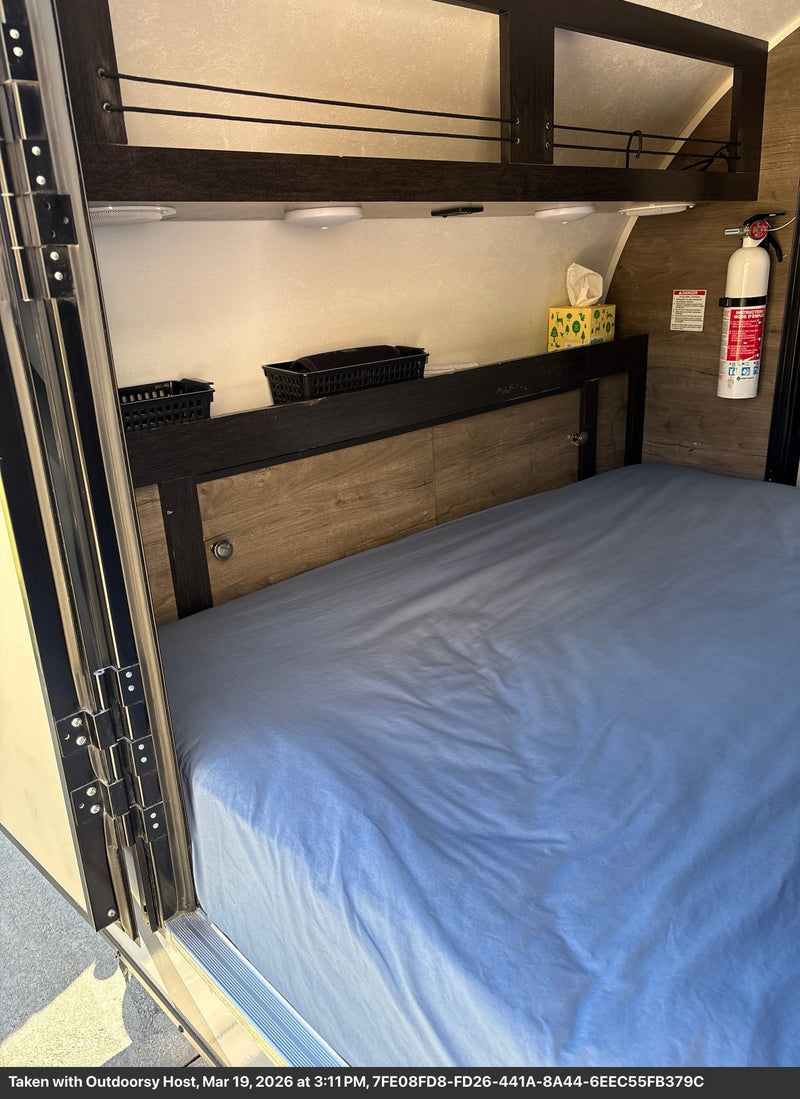  is parked and ready for an Outdoorsy adventure.|Inside this RV rental: a cozy bedroom with a blue bed — photo 2