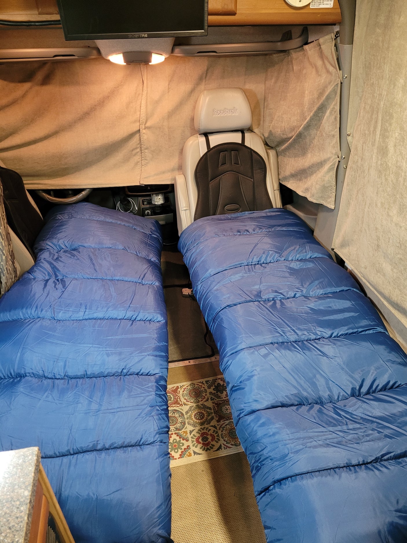 Two blue sleeping bags laid out in this cozy RV rental's camper van interior, perfect for overnight travel.