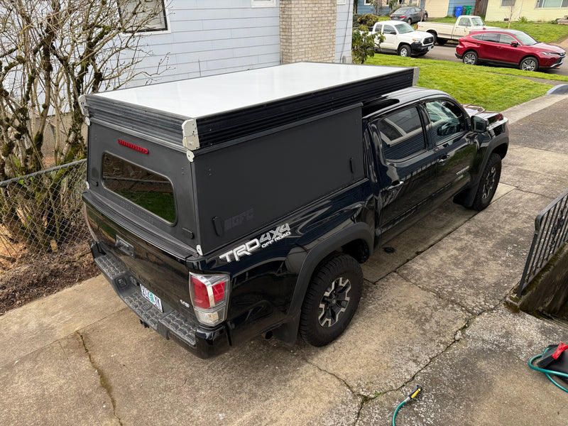 Black Toyota Tacoma 4x4 pickup with GFC pop-top camper shell. Perfect rv rental for off-road adventures and camping. — photo 3