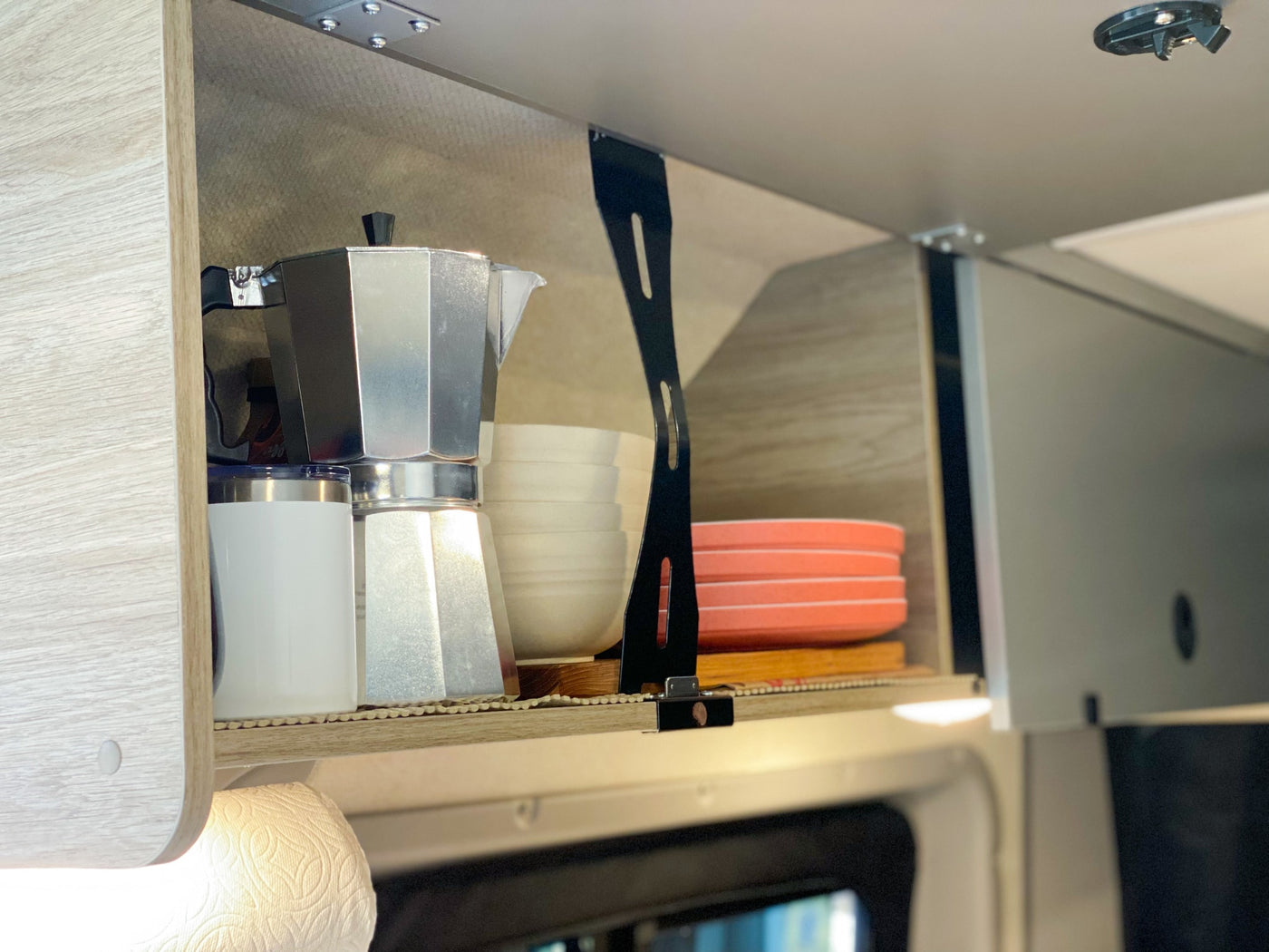 Inside an RV rental: Organized overhead kitchen cabinet with a moka pot, travel mug, bowls, and plates, perfect for camping. — photo 17