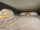Cozy RV rental bed with plush toy and book, offering a scenic outdoor view. Perfect for camping comfort and travel.
