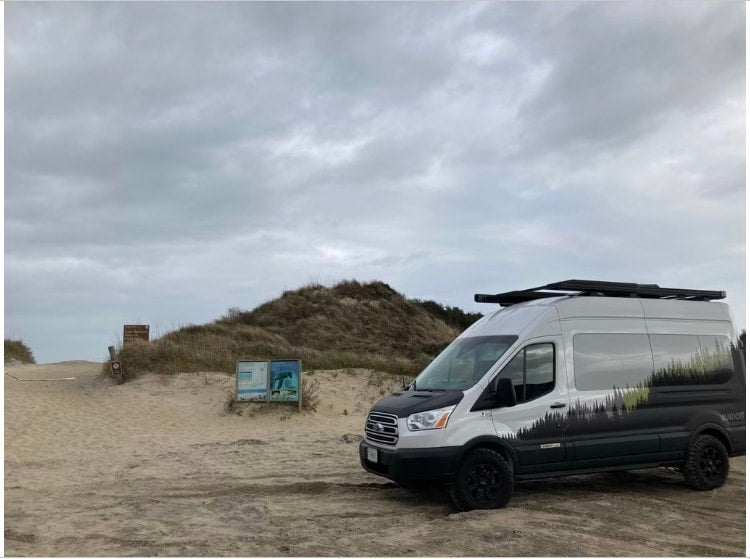 Adventure-ready RV rental van on a sandy path by dunes, perfect for beach trips under an overcast sky. — photo 9
