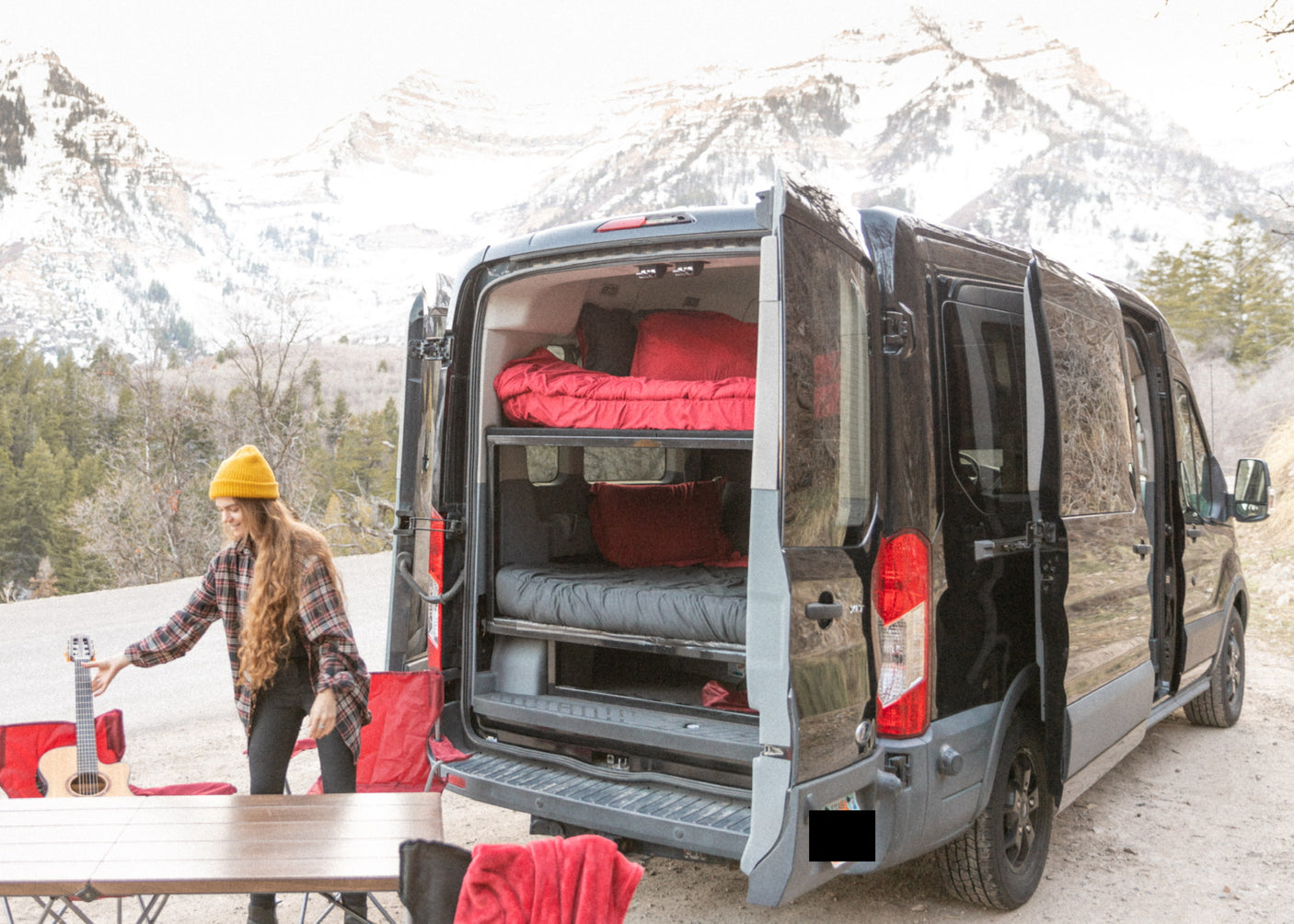 Ready for adventure? Our RV rental camper van, shown here with a woman and guitar, features bunk beds in a mountain setting.
