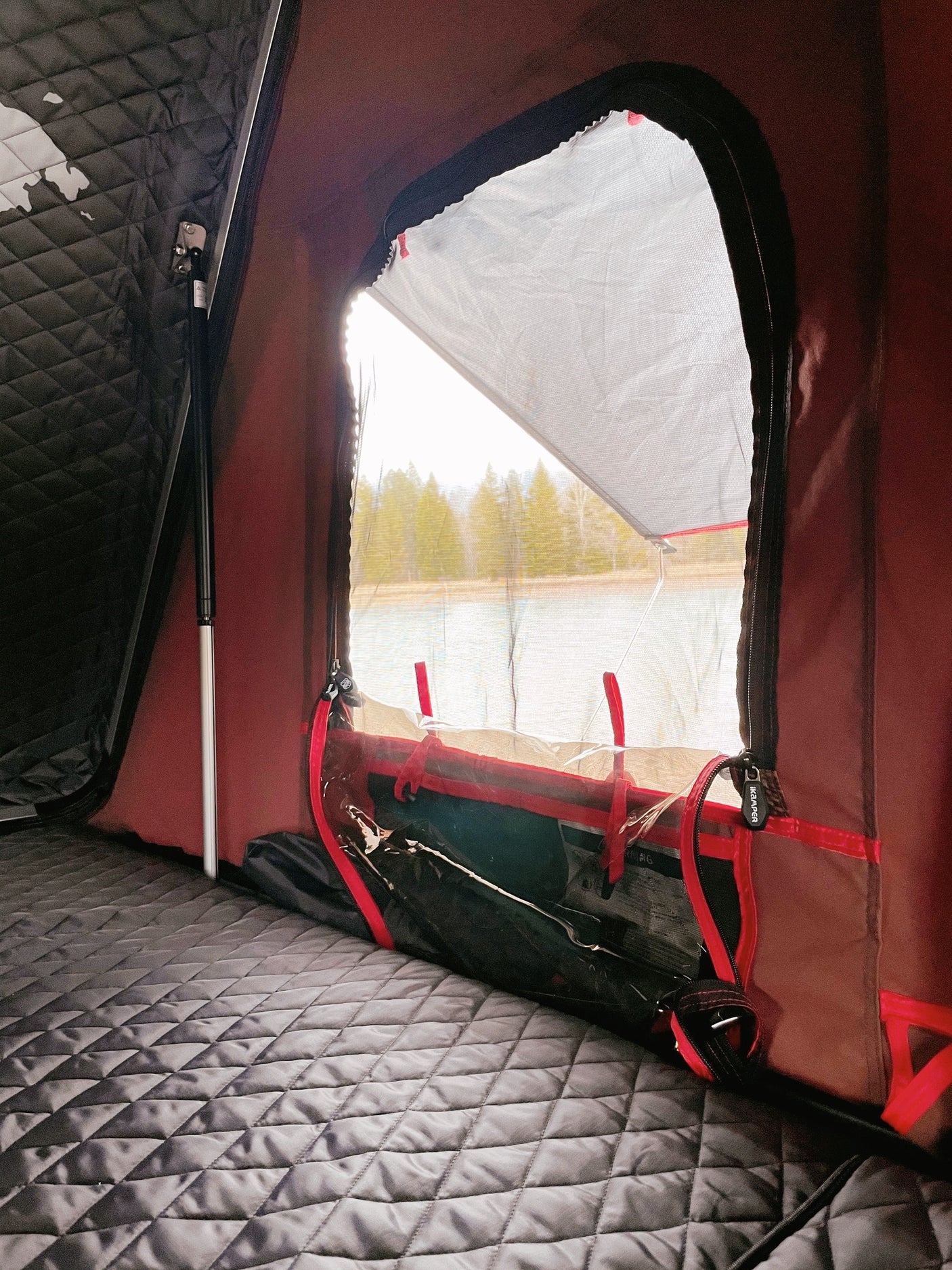 Cozy iKamper rooftop tent interior with lake view – perfect for your RV rental outdoor adventure.