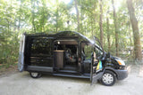 Black camper van for RV rental parked outdoors with doors open, revealing a sink and car seat inside.