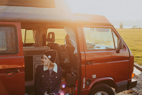 Golden hour serenity: a woman relaxes in her classic Westfalia RV rental camper van.