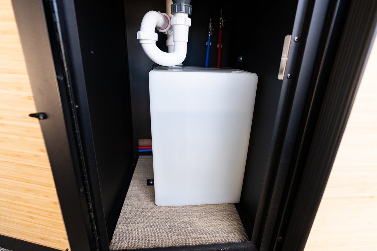 RV rental: Inside a cabinet, showing a water tank, white P-trap drain, and red/blue PEX water lines. — photo 15