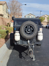 This black off-road trailer, perfect for an rv rental adventure, features a spare tire and propane tanks.