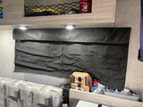 RV rental interior: Black blackout window shade, overhead netted storage, bright LED lights, and patterned seating.