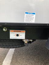 Essential safety warnings on an RV rental undercarriage, detailing wheel lug nut checks and tire raising.