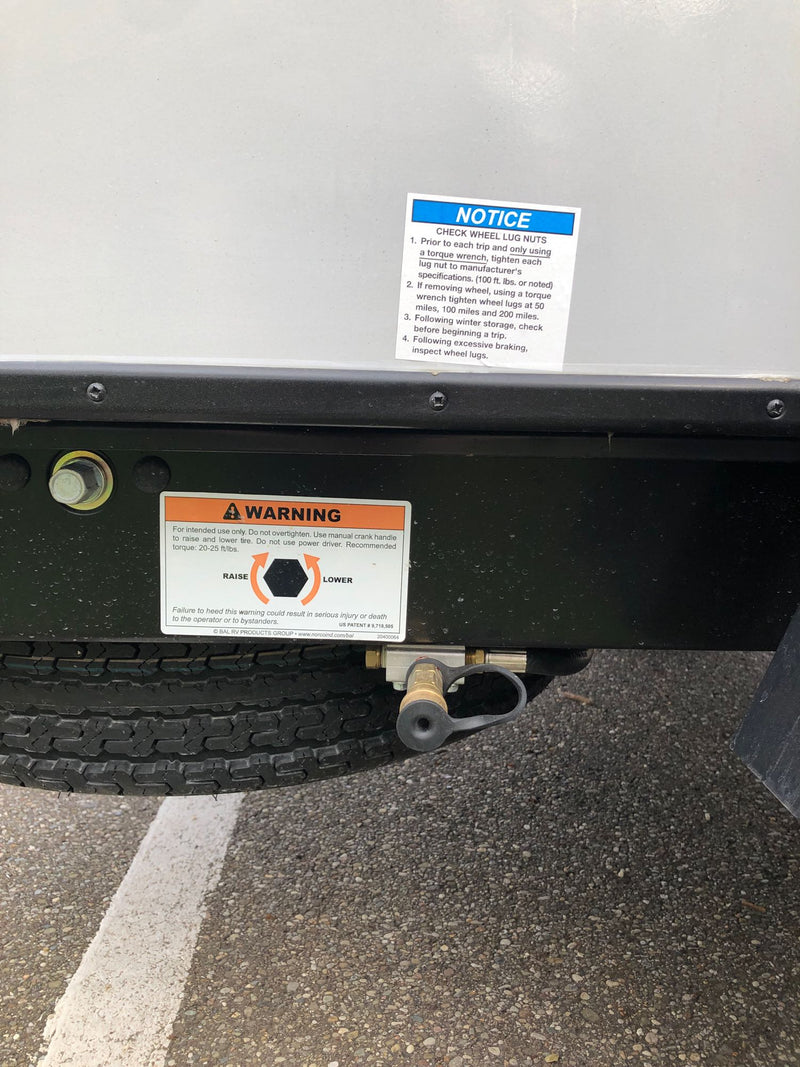 Essential safety warnings on an RV rental undercarriage, detailing wheel lug nut checks and tire raising. — photo 9
