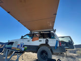 Overlanding SUV with an extended awning, a typical setup for an outdoor adventure or rv rental trip in the desert.