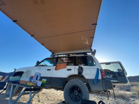 Overlanding SUV with an extended awning, a typical setup for an outdoor adventure or rv rental trip in the desert.