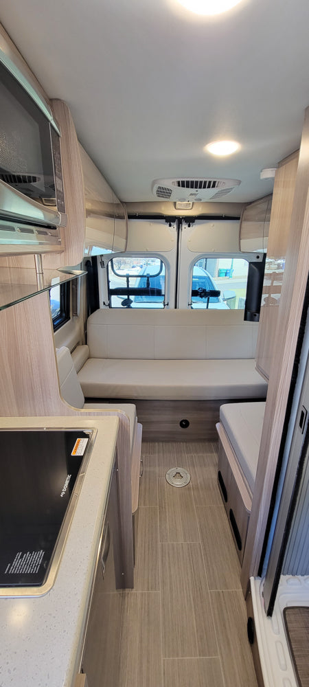 RV rental interior: kitchen with stove & microwave, rear seating/bed, and clean, modern design for travel.