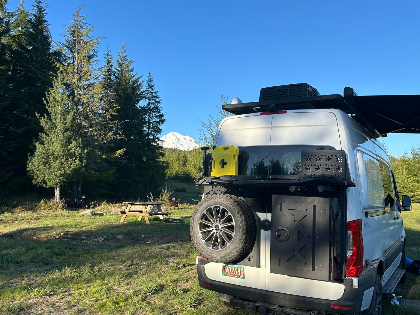  parked in a scenic mountain meadow for off-grid adventure.|An RV rental campervan at a stunning mountain campsite — photo 13