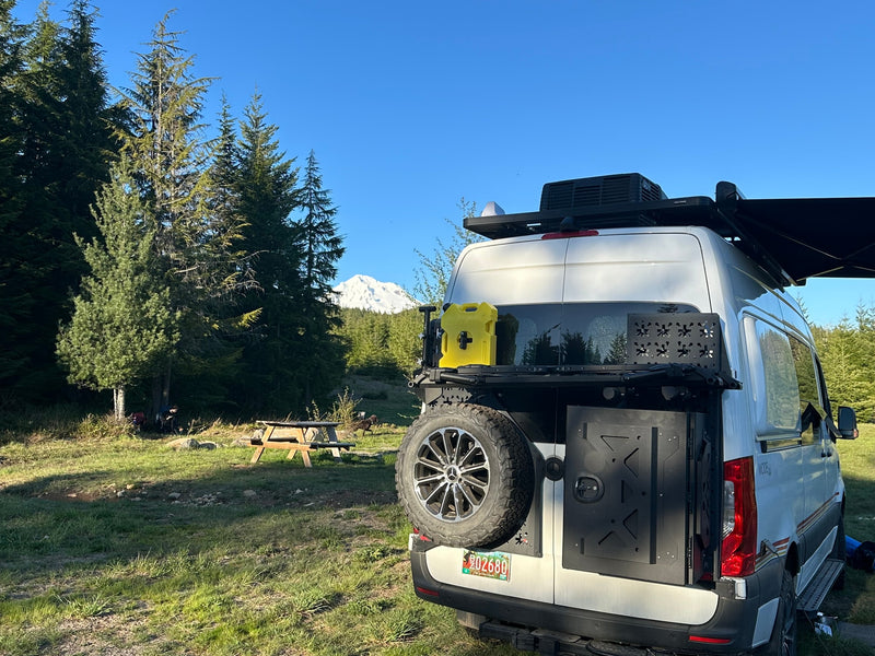  parked in a scenic mountain meadow for off-grid adventure.|An RV rental campervan at a stunning mountain campsite — photo 13