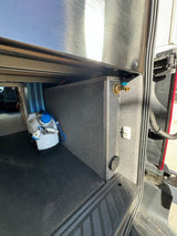 Organized utility area of an RV rental van: includes a portable water tank, custom fabric storage, and hookups.