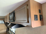 Compact RV kitchen with microwave, cabinets, and control panels. Ideal for your next RV rental adventure.