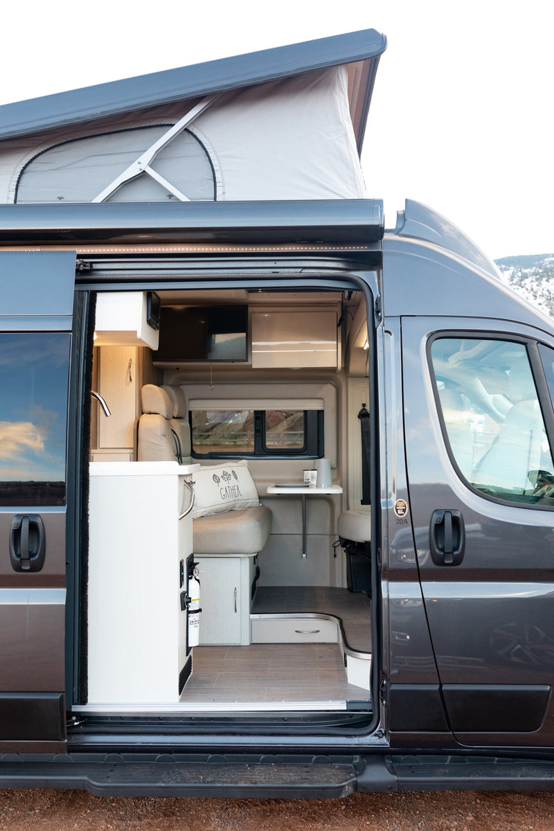  with pop-top & awning extended on red dirt. Illuminated interior invites adventure.|Spacious gray pop-top camper van for rv rental — photo 2