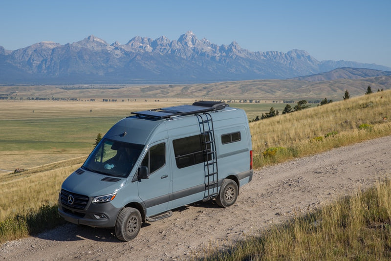 A light blue Mercedes Sprinter camper van on a dirt road — photo 1