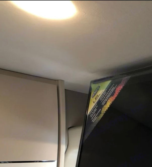 RV rental interior: A TV with a colorful label sits beside a built-in cabinet or refrigerator, showcasing efficient use of compact space.
