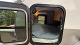 Cozy rv rental interior with a comfy bed visible through the open door of a compact camper.
