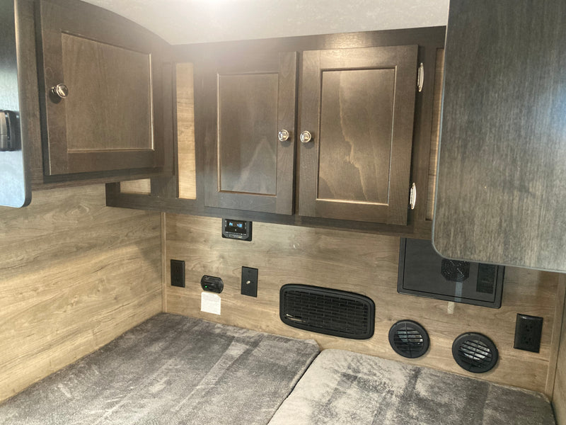 RV rental bunk with overhead cabinets, electrical outlets, and ventilation system. — photo 5