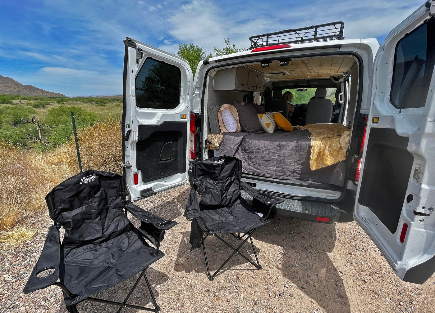 Your RV rental destination. Cozy camper van with bed and outdoor chairs setup for a peaceful camping experience in the desert. — photo 8