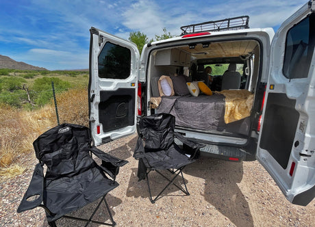 Your RV rental destination. Cozy camper van with bed and outdoor chairs setup for a peaceful camping experience in the desert.