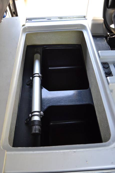 RV rental: A deep, black-lined storage compartment inside, featuring a secured silver pole & dual power outlets.