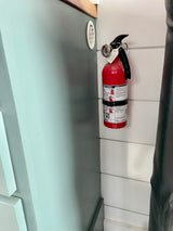 Essential safety for your RV rental journey: a red fire extinguisher mounted in the vehicle, ready for emergencies.