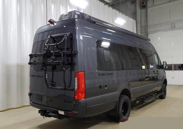  parked on a sunny street next to a silver Ford Bronco.|Dark grey Mercedes-Benz Sprinter van RV rental — photo 3