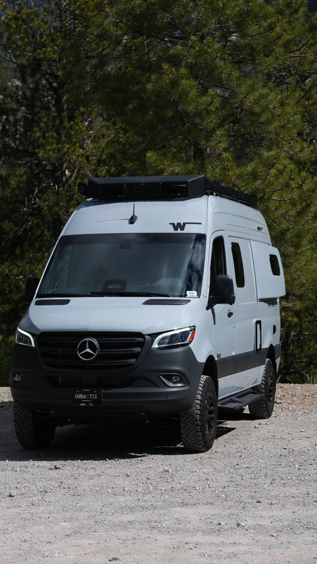 Light grey Mercedes-Benz Sprinter camper van with off-road tires, perfect for an RV rental nature escape.