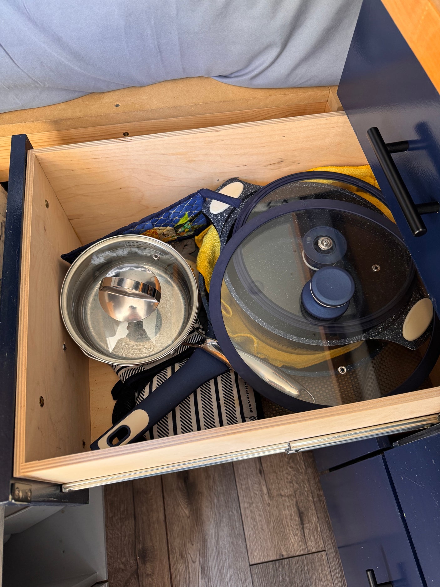 This RV rental drawer is efficiently packed with kitchen essentials: a pot, pan with lid, and towels for cooking on the go.