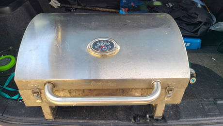 An "Aussie" portable stainless steel BBQ grill in an RV rental trunk, ideal for camping adventures.