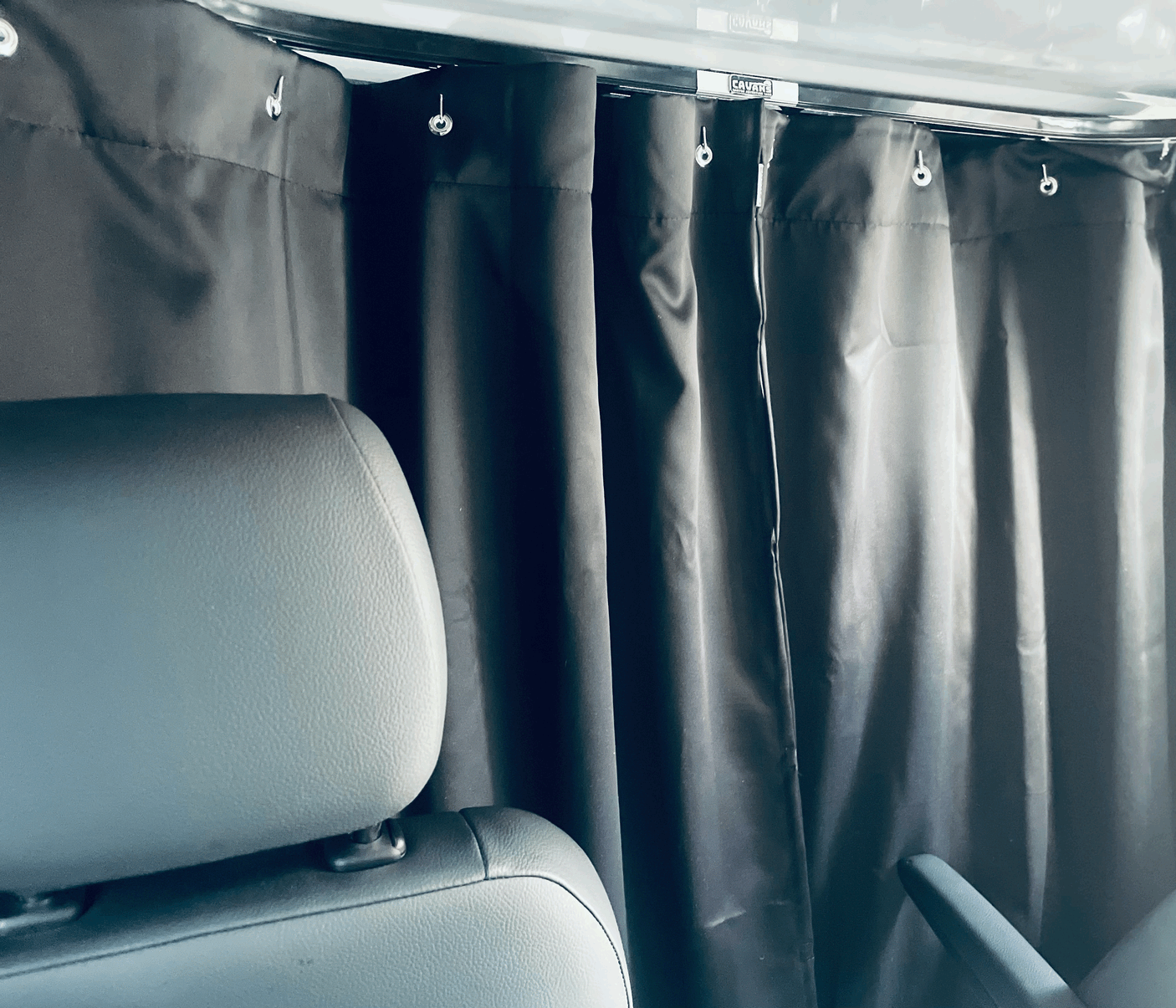 RV rental interior: black privacy curtains with CAVANS branding and passenger seat.