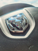 Close-up of a chrome Ram logo on a black textured steering wheel, perfect for your RV rental adventure.