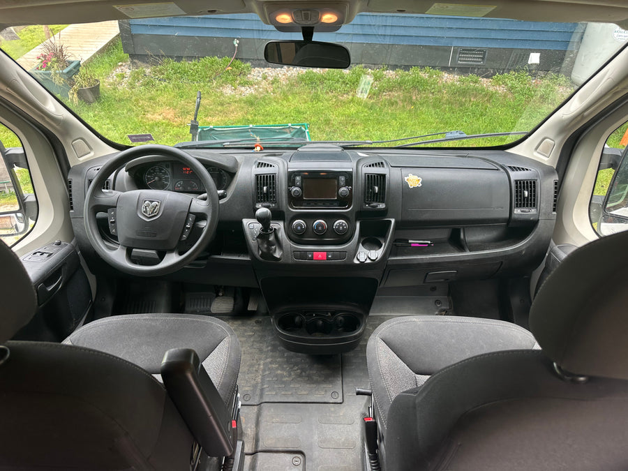 Step inside this RV rental! Driver's perspective shows the dashboard, steering, and wide view of a grassy yard.