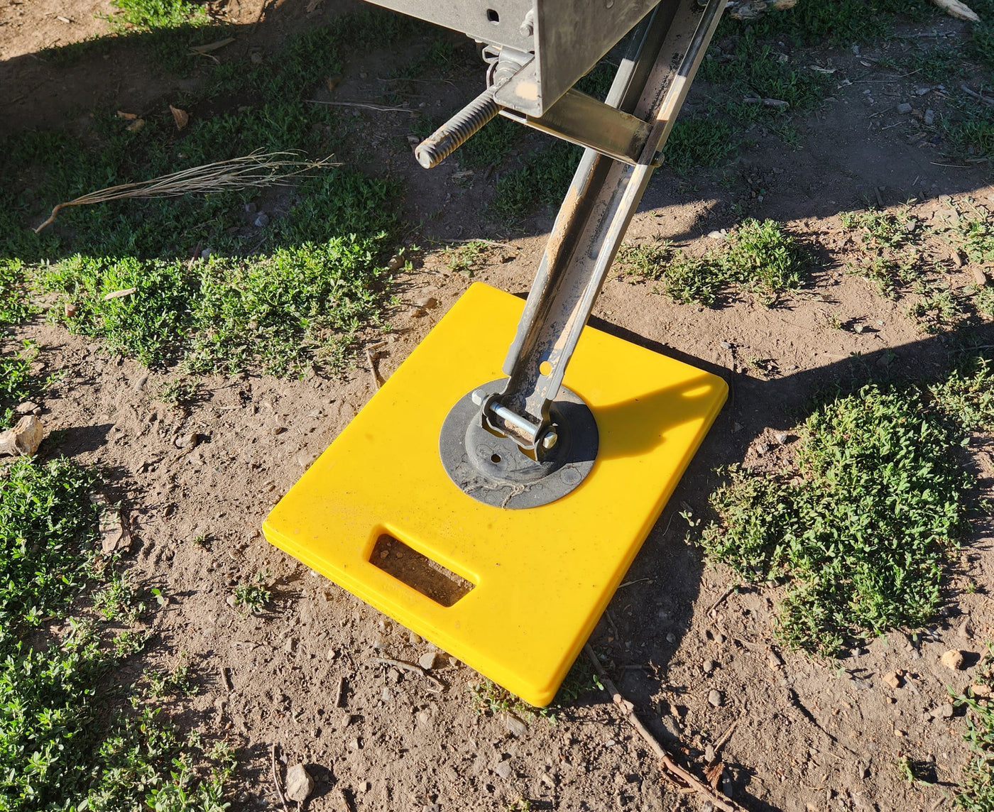 RV rental setup: A yellow pad stabilizes an RV jack on dirt, essential for level camping. — photo 18