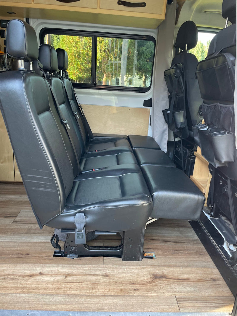 Comfortable RV rental interior: black flexible seating for passengers, wood-look floor, and windows, ideal for travel. — photo 5