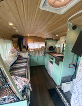 Explore this cozy RV rental's interior! Wood ceilings, mint kitchen, and comfy beds offer a charming tiny home on wheels experience.