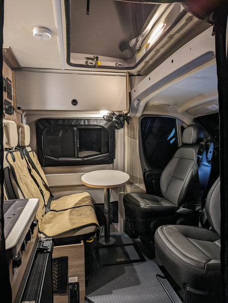 Well-equipped rv rental camper van interior featuring swivel seats, a compact table, and storage for road trip comfort.