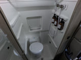 Compact RV rental wet bath with an integrated shower and toilet, featuring hanging toiletries and a small storage shelf.