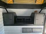 RV rental: Camper interior with dark storage cabinets, central platform, control panel, and a pop-top tent section above.